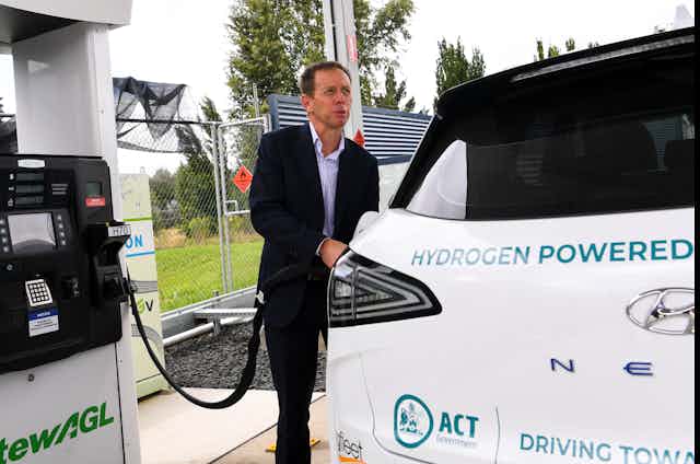 Man fills a car with hydrogen fuel