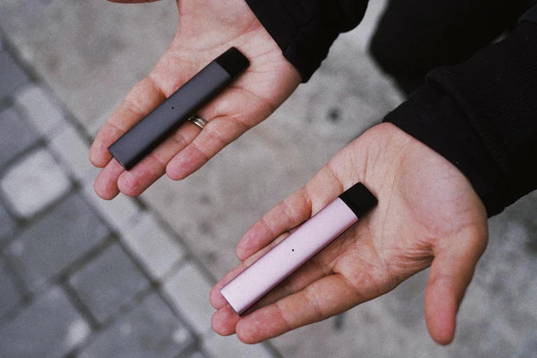 Person holding two vapes, one in each hand, palm up