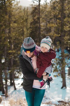 Woman walking outdoors in winter with a baby in her arms
