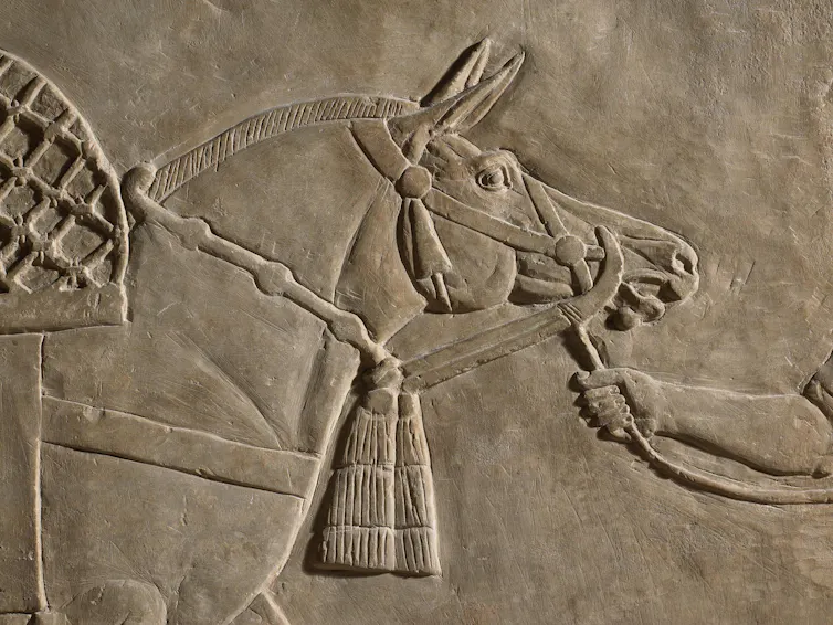 An ancient stone carving showing people with horses.