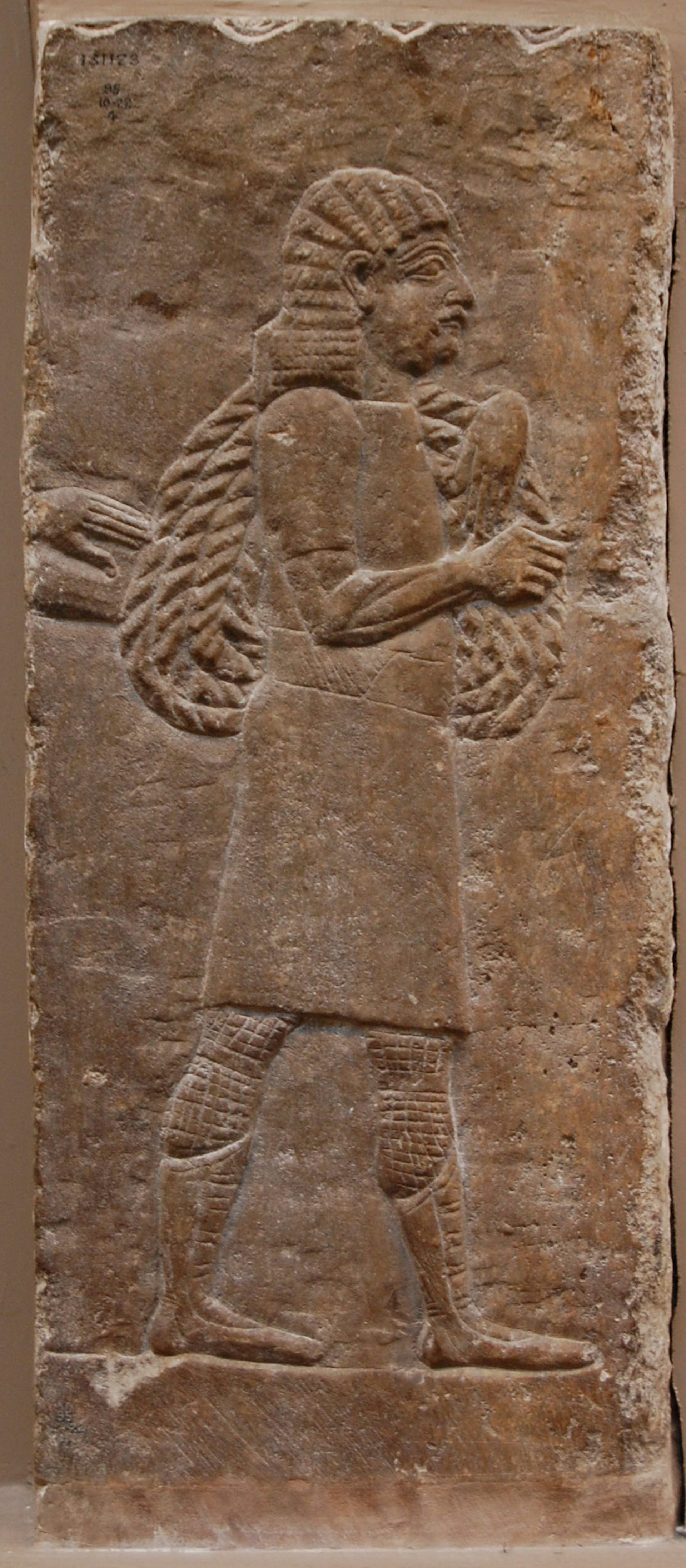 An ancient stone carving showing people carrying things.
