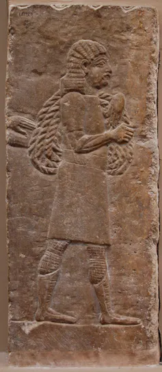An ancient stone carving showing people carrying things.