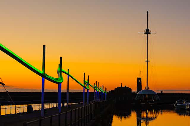 Sunset over a promenade with a green light feature.
