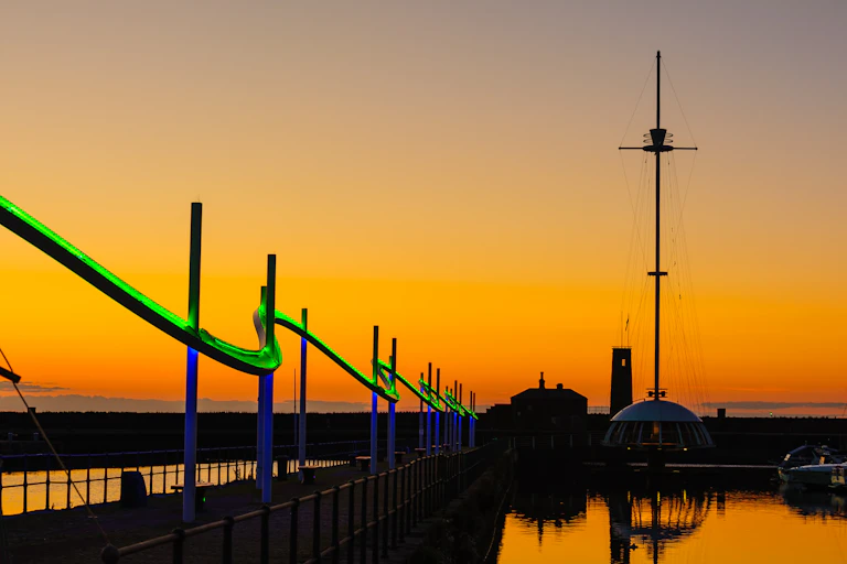 Sunset over a promenade with a green light feature.