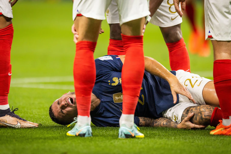 A footballer on the floor in pain.
