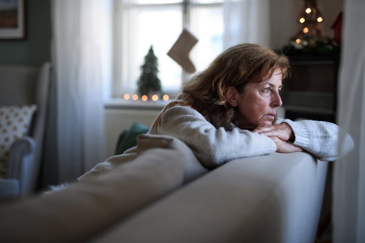 Lonely senior woman sitting on sofa indoors at Christmas