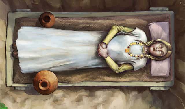 An illustration shows a blonde woman in repose in her burial, lying on a wooden bed and wearing a gold necklace.
