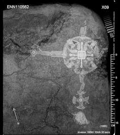 A shadowy X-ray shows on the left hand side an item that looks to be a large crucifix