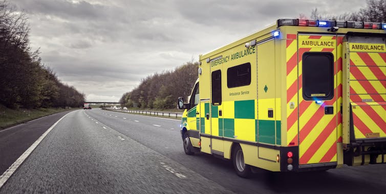 An ambulance on a country highway under grey skies.