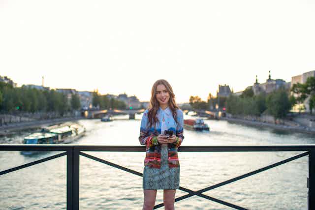 A woman stands on a bridge in Paris.