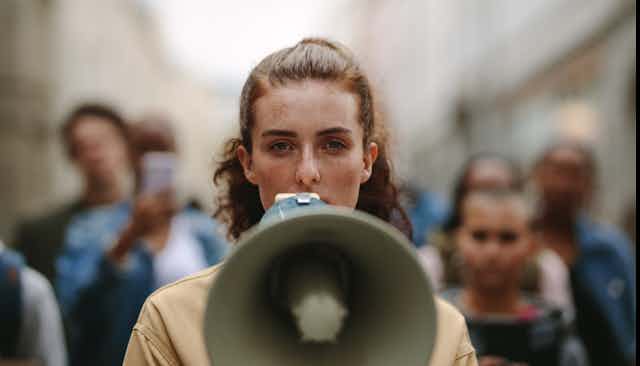 Une jeune femme tient un porte-voix devant son visage