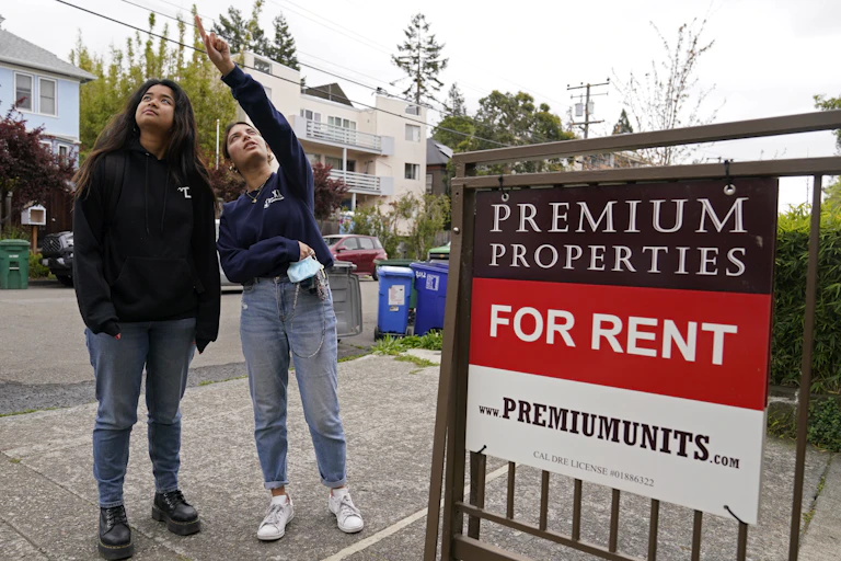 Students seen in front of a for rent sign.