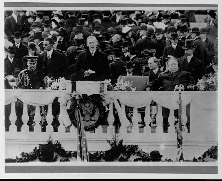 A man is surrounded by a crowd of people as he delivers his speech.