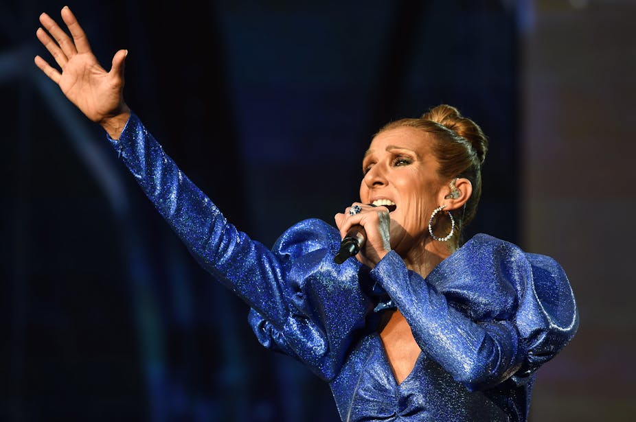 Dressed in a royal blue gown, Celine Dion performs on stage.