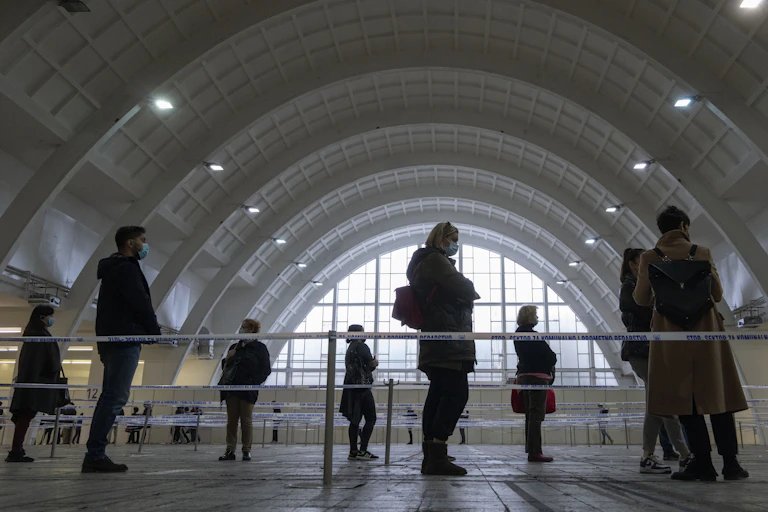 people stand in a queue to be vaccinated in a cavernous hall