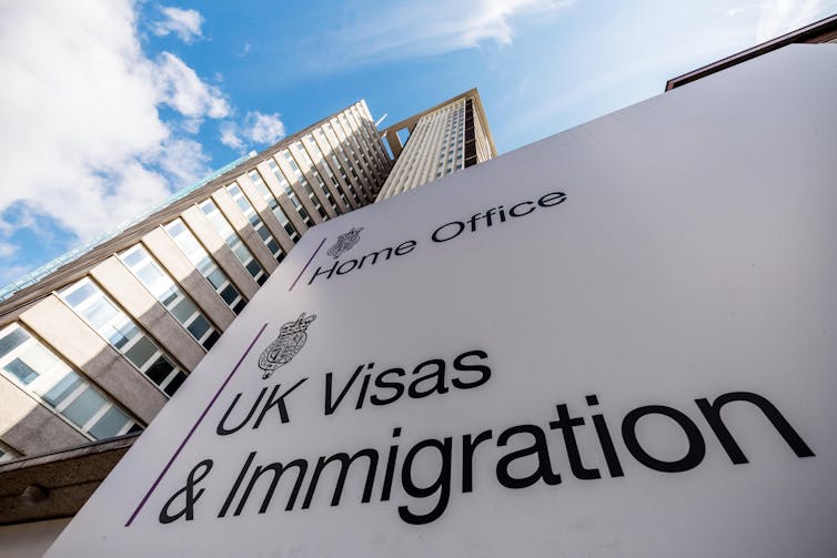The sign to the UK Visas and Immigration centre in Croydon with a large building towering in the background
