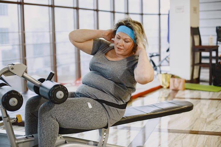 Woman doing sit ups in a gym.