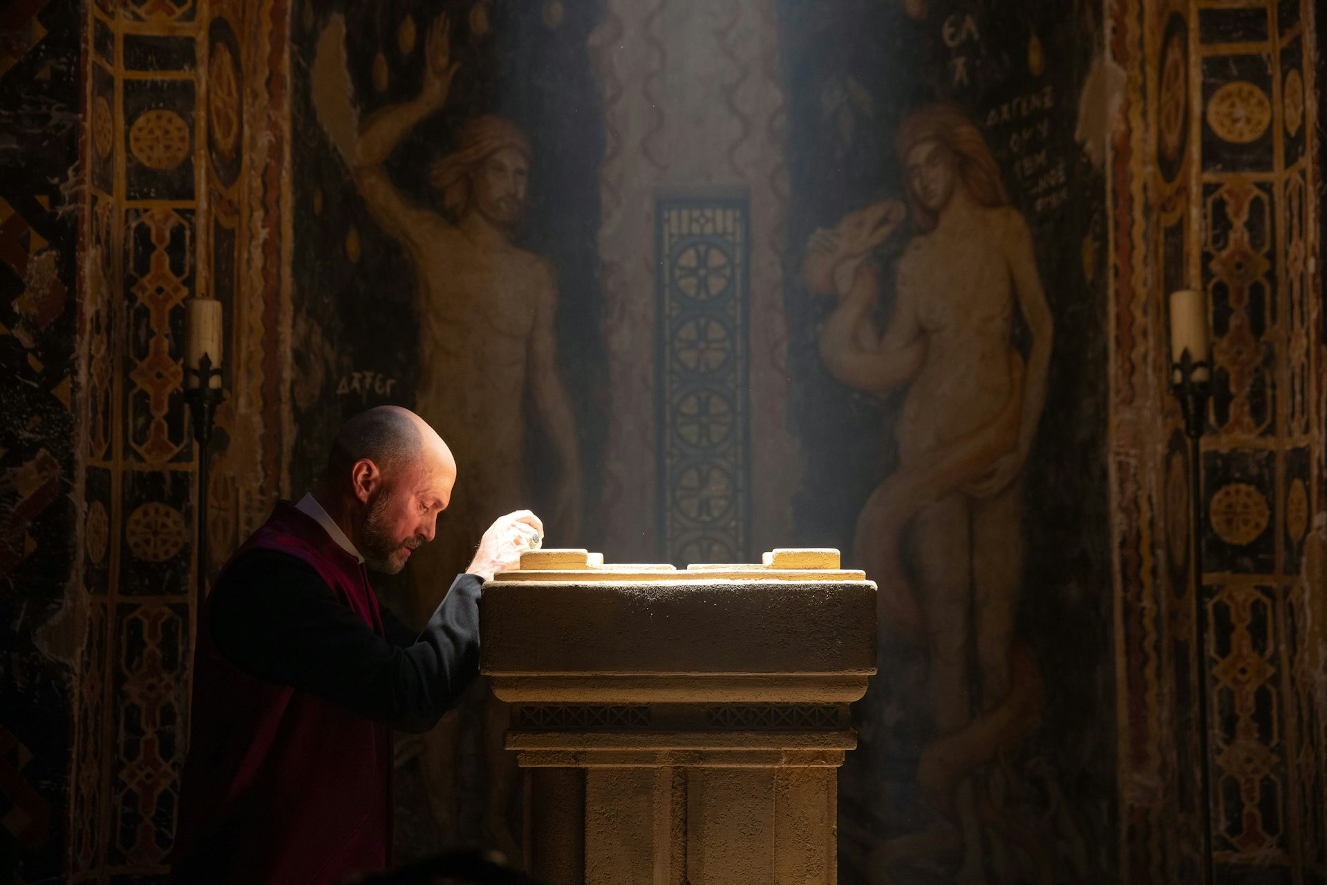 A priest kneels to pray in the Magisterium.