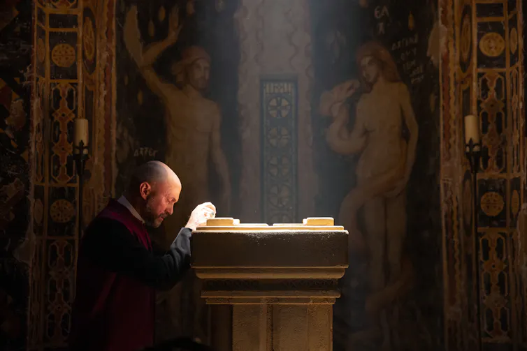 A priest kneels to pray in the Magisterium.