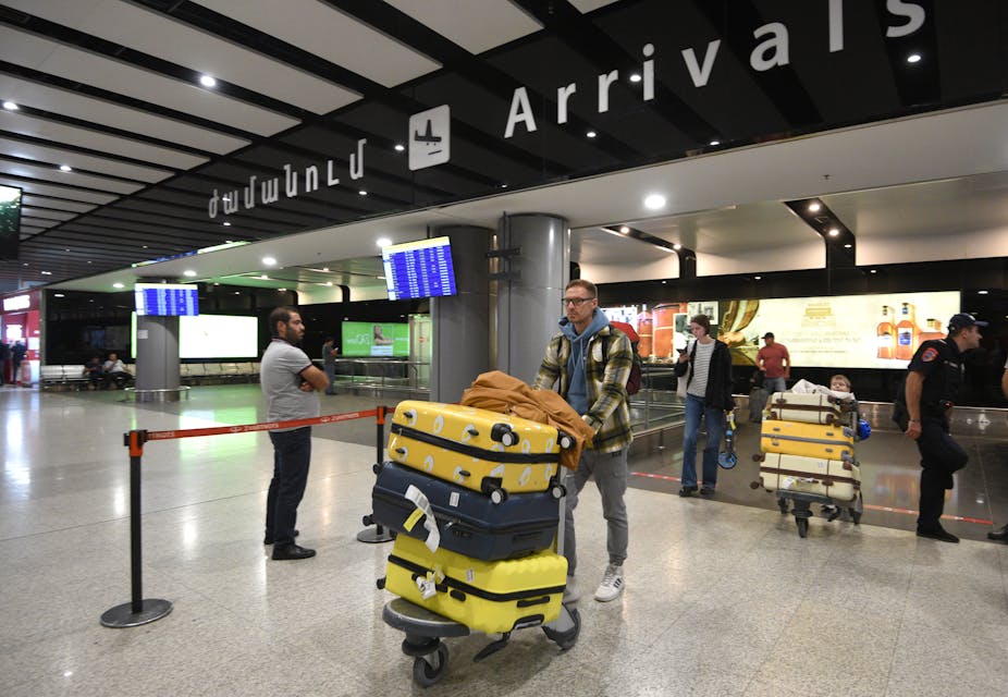 Des personnes arrivent dans la zone d'arrivée d'un aéroport avec leurs bagages