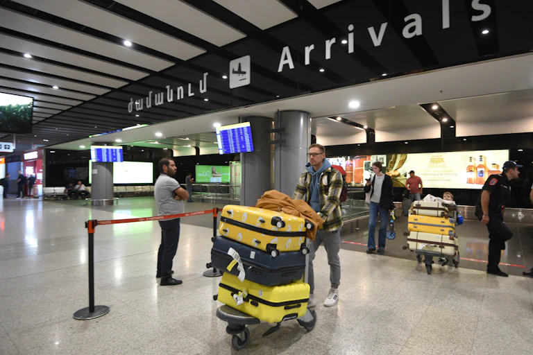 Des personnes arrivent dans la zone d'arrivée d'un aéroport avec leurs bagages