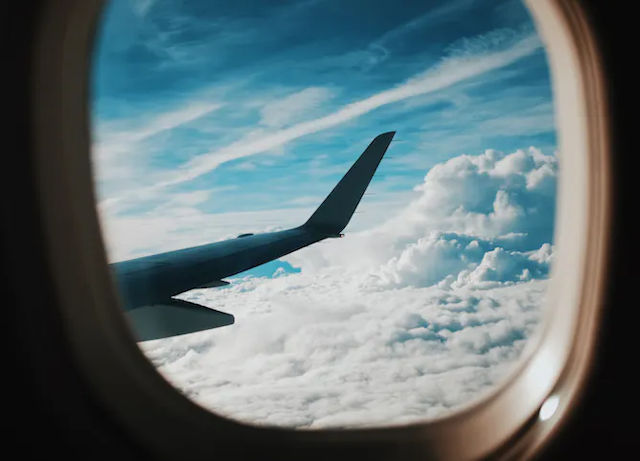 Sayap pesawat di langit biru yang terlihat dari jendela pesawat
