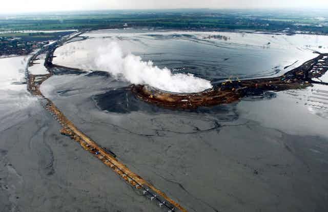 aerial view of muddy wet plain with steam rising from a structure
