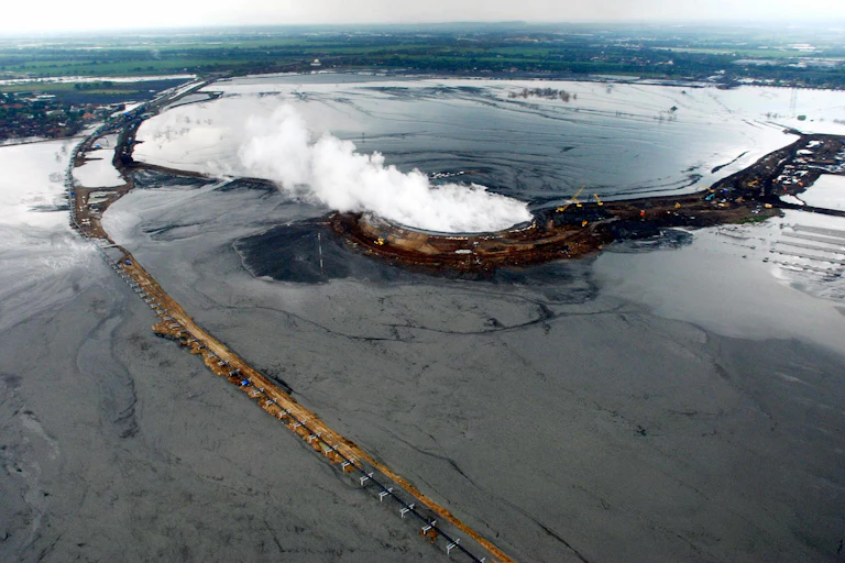 aerial view of muddy wet plain with steam rising from a structure