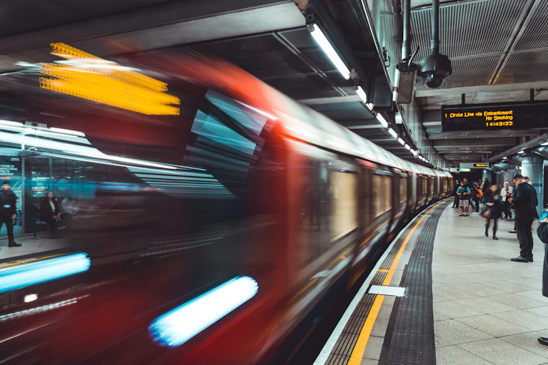 A train driving past a busy London Underground platform.