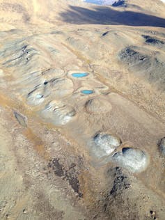 aerial view of landscape with round holes filled with liquid and mud