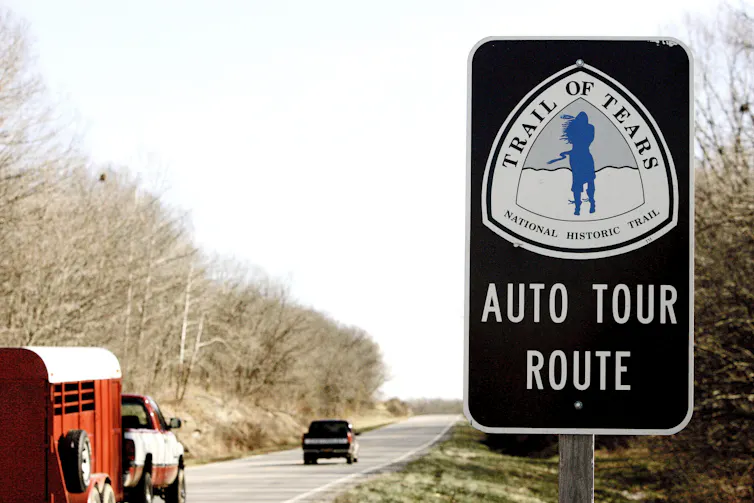 Cars travel along a highway. A sign in the foreground reads Trail of Tears Auto Tour Route.
