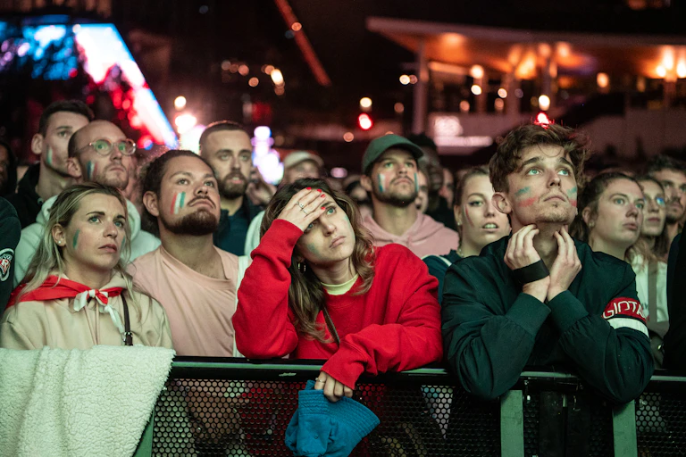 A group of people watch the world cup on a big screen.