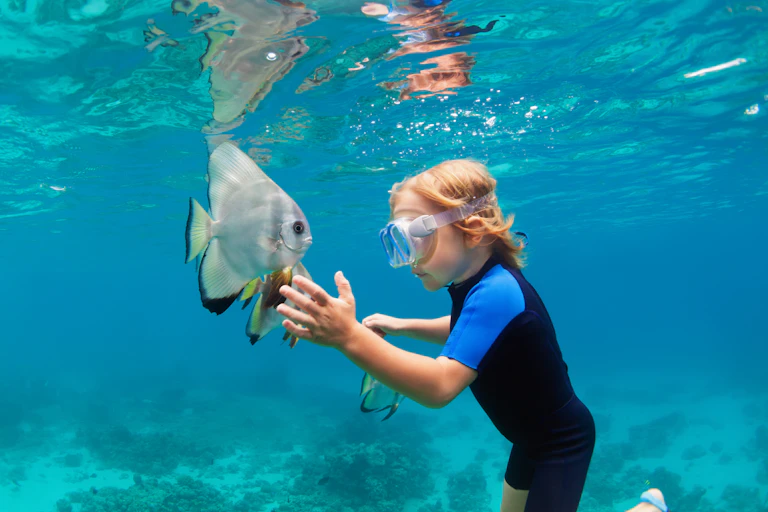 boy reaches out to fish underwater