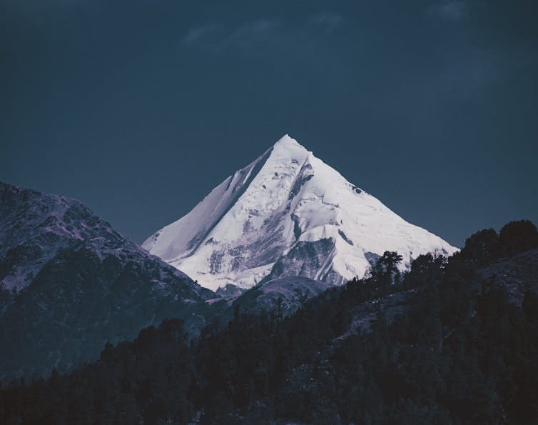 A photo of a snow-covered mountain peak among hills.