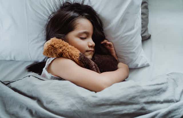Sleeping child holds a soft toy