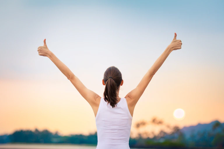 Young woman holding arms aloft.