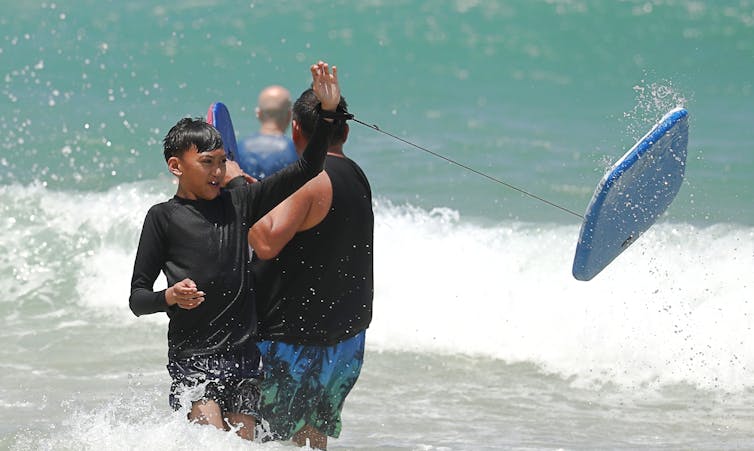 boy with boogie board and other swimmers