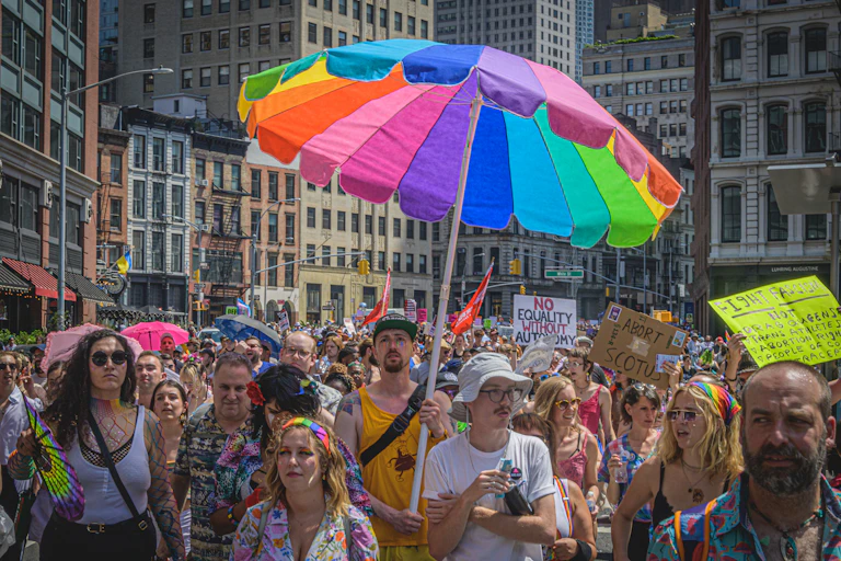 Large group of LGBT people marching and holding signs.
