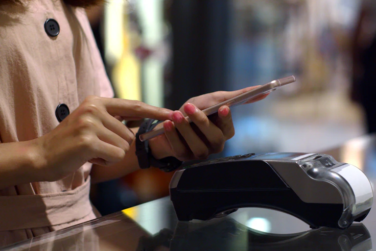 Woman using phone near store's EFTPOS terminal..