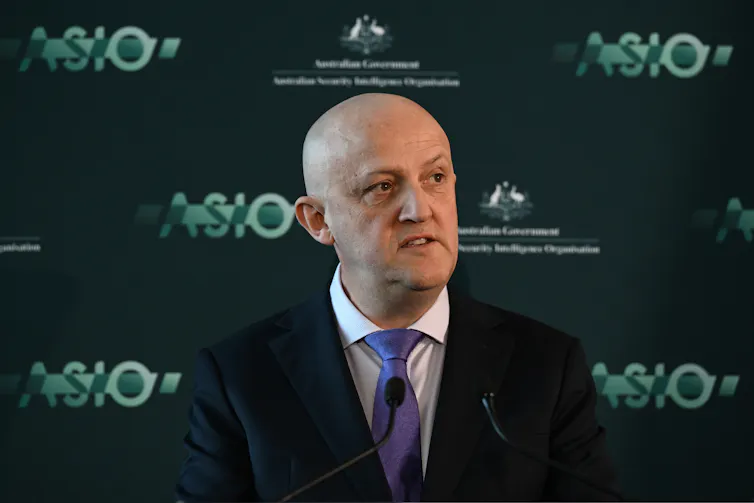Man in a suit in front of ASIO sign