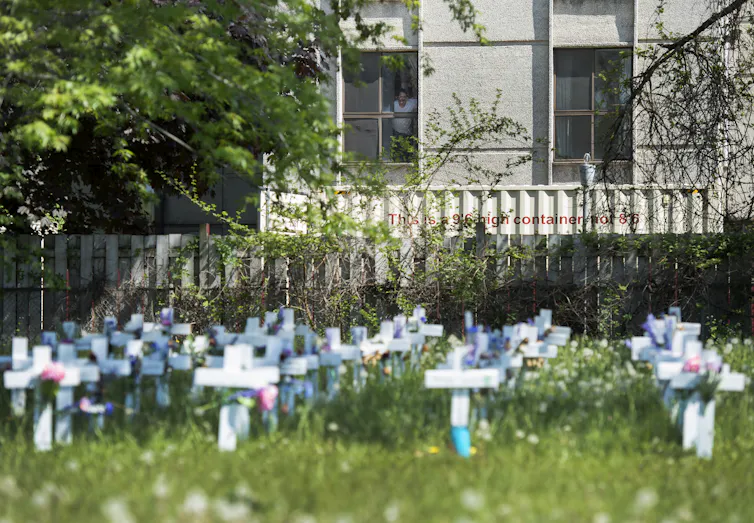 Small crosses in grass with a building in the background
