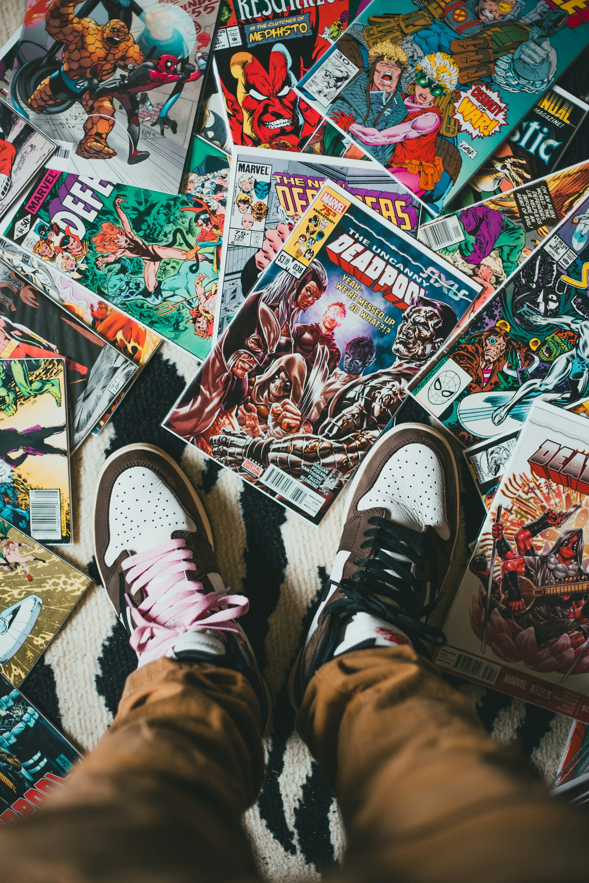 A pair of trainers/sneakers standing on an array of Marvel comics.