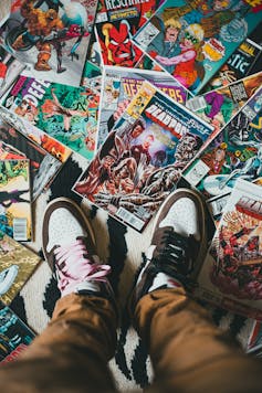 A pair of trainers/sneakers standing on an array of Marvel comics.