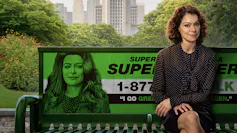 Jennifer Walters sits on a bench emblazoned with her She-Hulk alter ego's face.