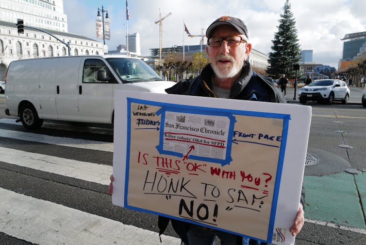 Man in baseball cap holds up a placard