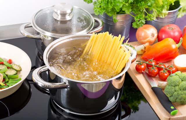 Spaghetti boilding in a saucepan on a ceramic hob.