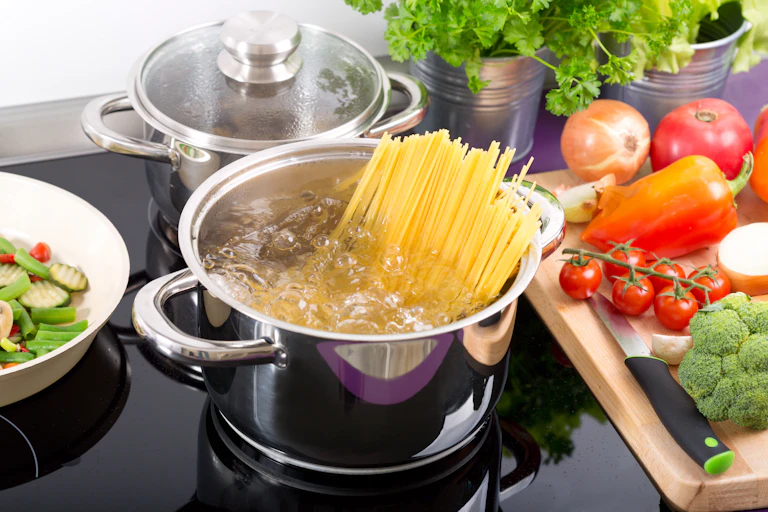 Spaghetti boilding in a saucepan on a ceramic hob.