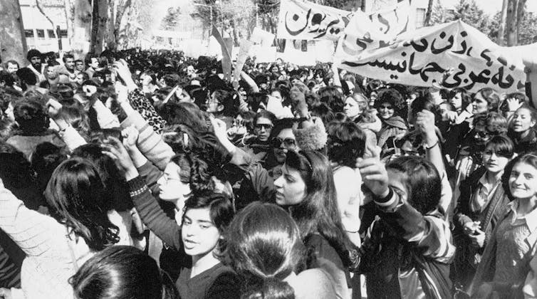 A black and white picture showing hundreds of young girls marching in a procession and holding up banners.