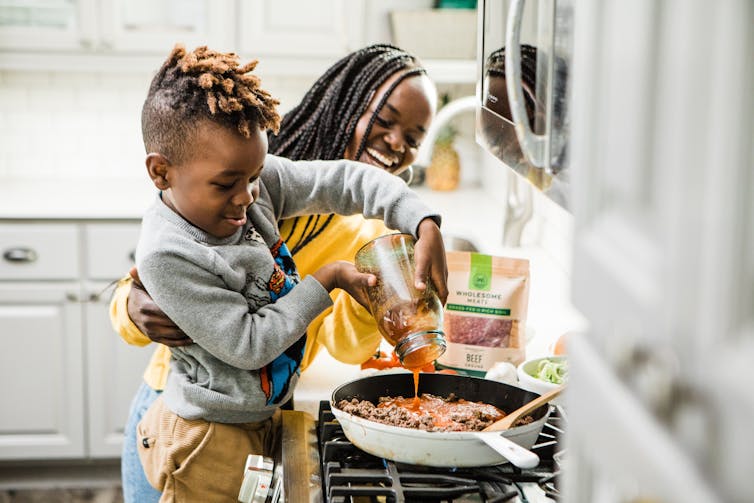 Mum helps child cook a pasta sauce