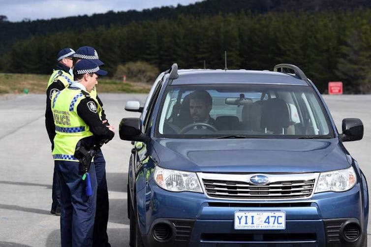 Police officers standing next to a car.